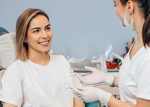 Woman in dental chair listening to her Brenham dentist talk