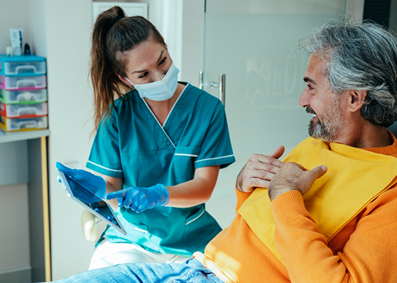 Dentist showing a tablet to a patient in the dental chair