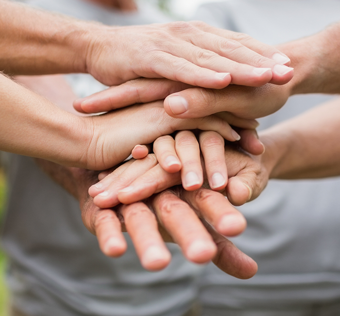 Group of people standing in a circle and putting their hands together in the middle
