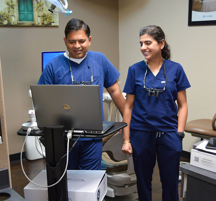 Two dentists looking at a laptop in a dental treatment room