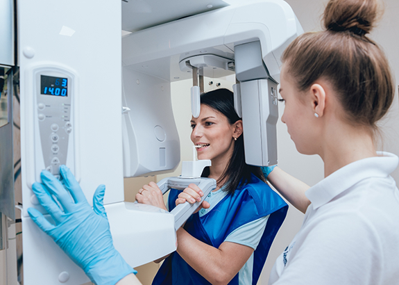 Woman getting a C T cone beam scan of her jaws and mouth in a dental office