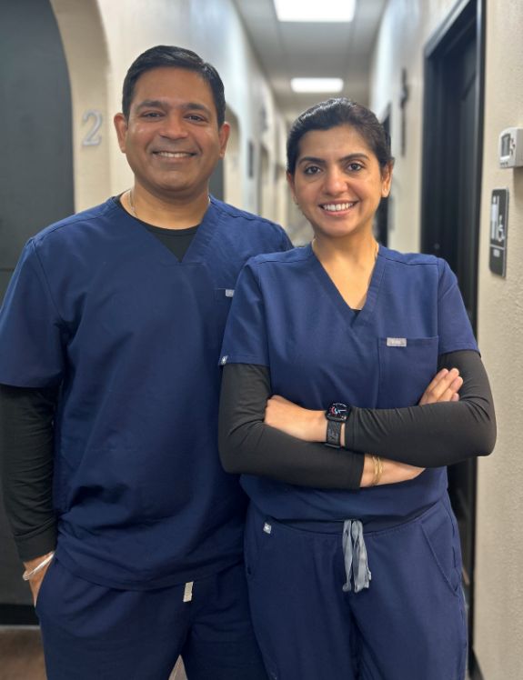 Brenham dentists Doctor Sumeet Sharma and Doctor Saru Sharma smiling in blue scrubs