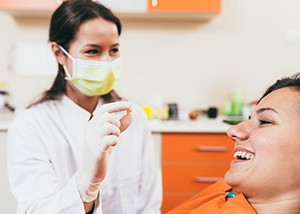Dentist showing a smiling patient her extracted tooth