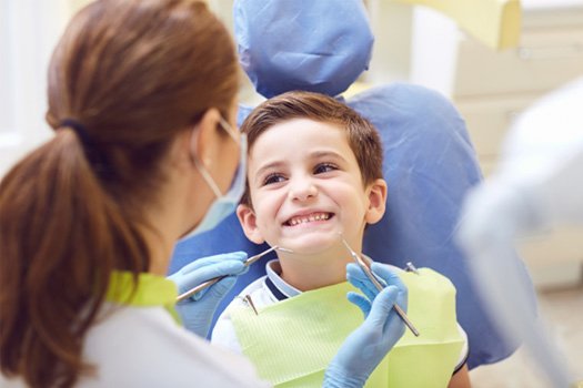 Little boy smiling at dentist about to examine his teeth