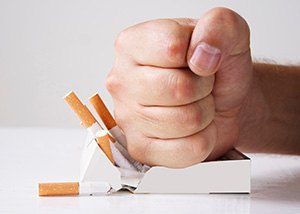 Fist smashing a pack of cigarettes