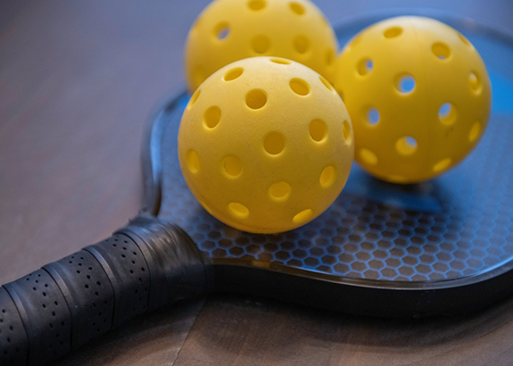 Pickleball racket with three yellow balls
