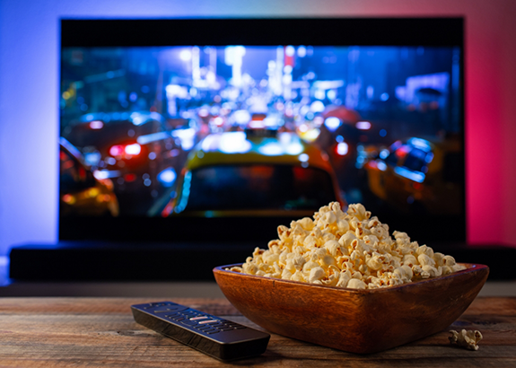Bowl of popcorn on a coffee table in front of a T V
