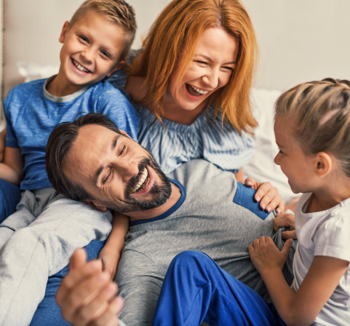 Family of four laughing together on a couch