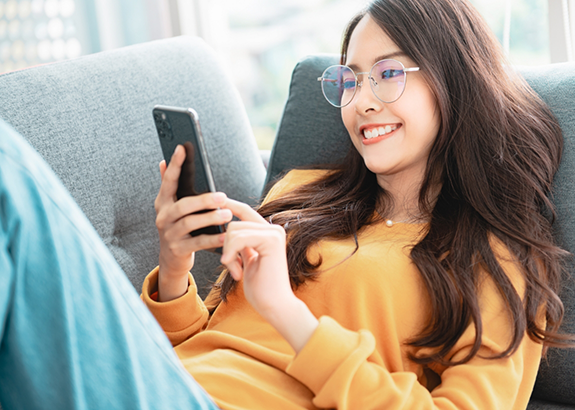 Young woman smiling while looking at her phone
