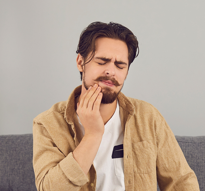 Man holding the side of his jaw and wincing before T M J treatment