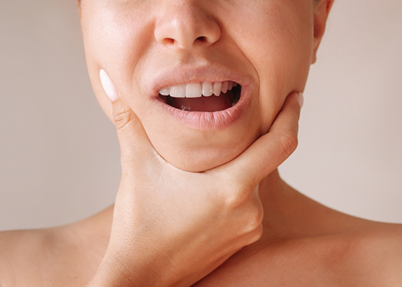 Person holding both sides of their jaw in pain