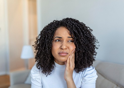 Woman experiencing jaw pain at home