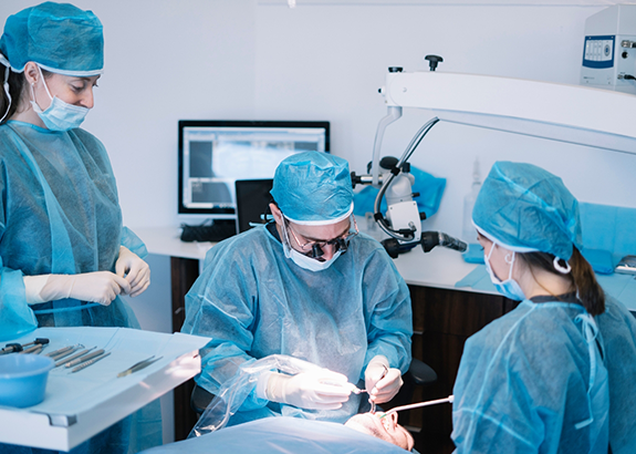 Dentist and two assistants performing wisdom tooth extractions on a patient